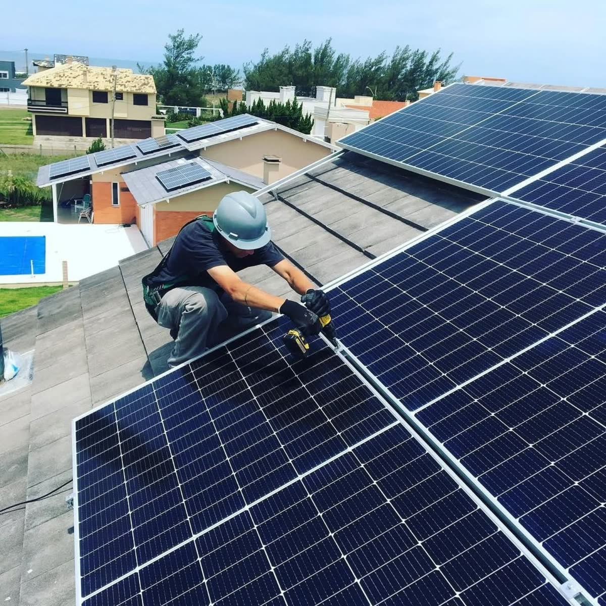 Técnico com capacete e luvas instalando painel solar